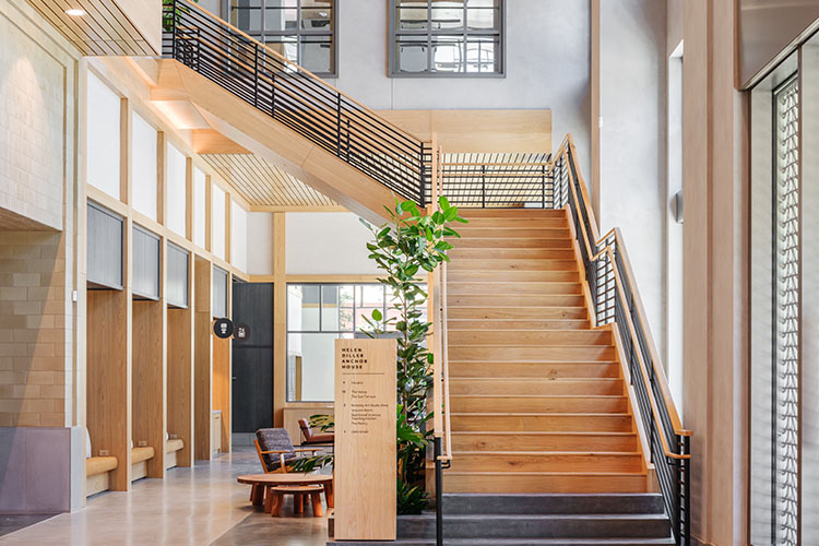 A spacious lobby shows a staircase leading to another floor. There are several smaller lounging areas near the staircase.