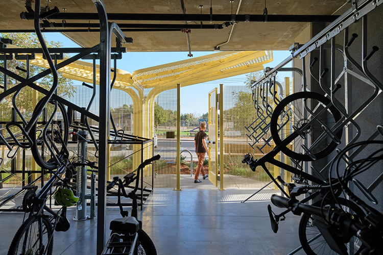 Several bikes are stored in the secure bike storage area. A man is exiting the area through a door that leads to the street.